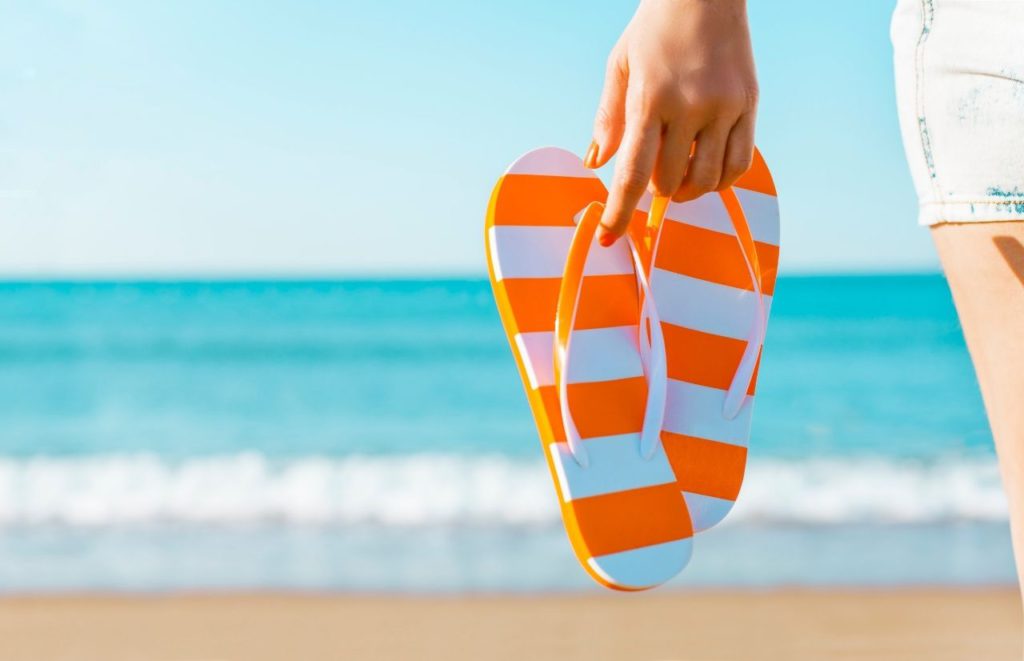 Orange and White Flip Flops on Florida Beach. Keep reading to get the best souvenirs from Florida.