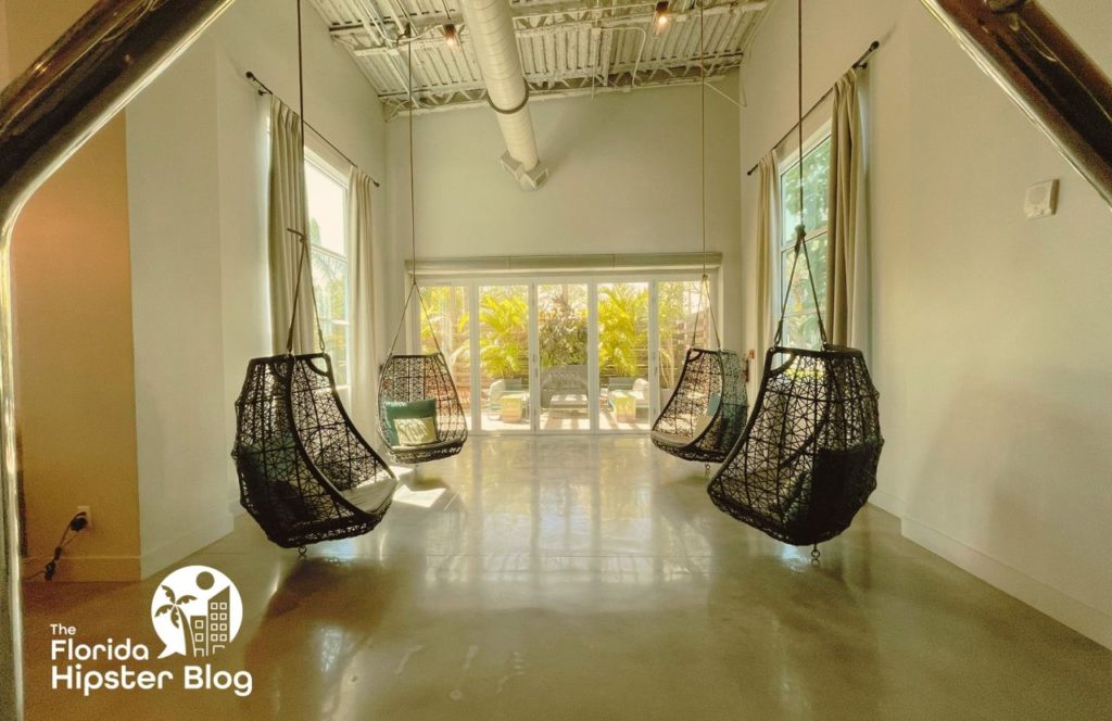 Things to do in Tampa Bay, Florida Hotel Alba. Sitting area with hanging wicker chairs with industrial touches in the room. Keep reading to discover all you need to know about Hotel Alba Tampa. 